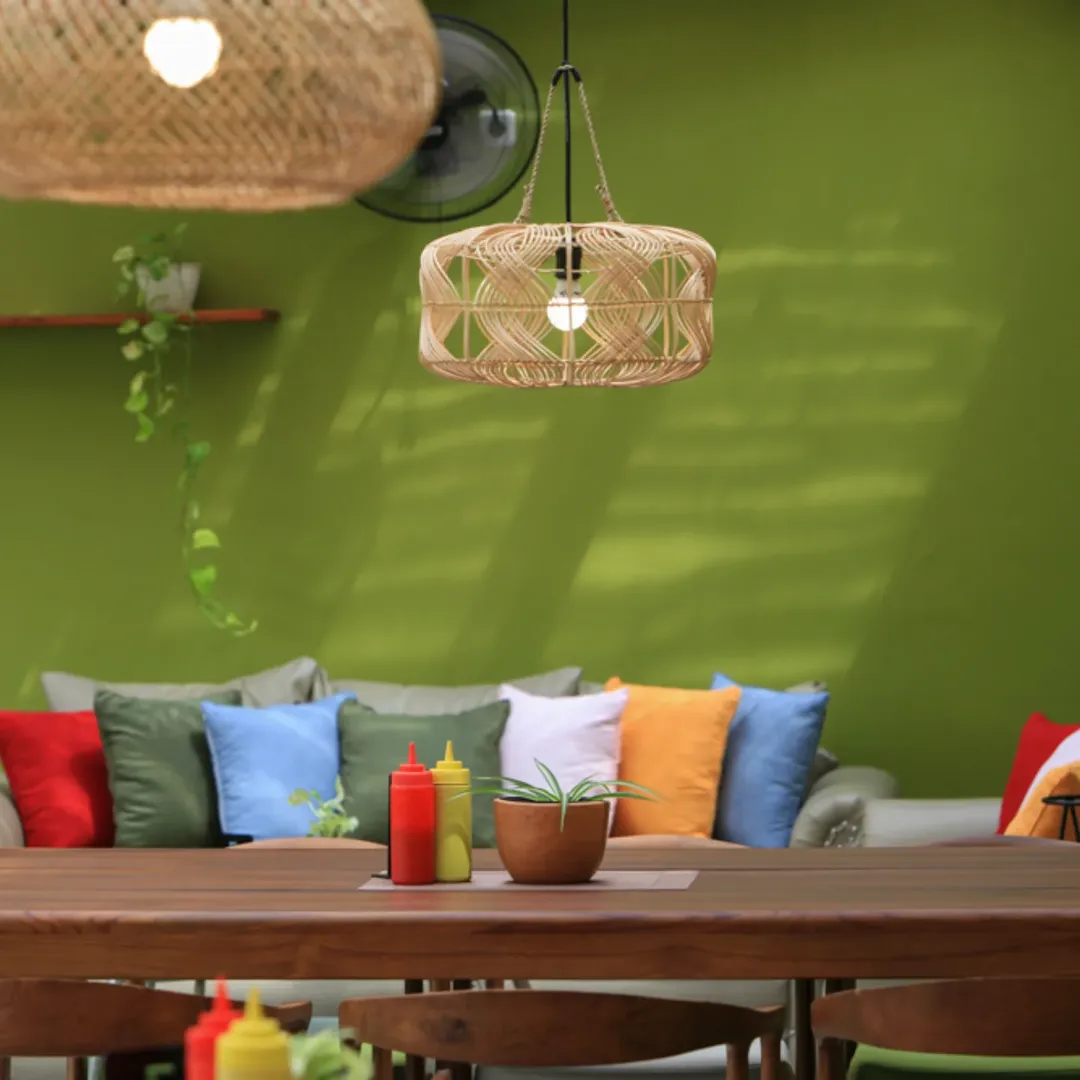 Area sofa nyaman dengan bantal warna-warni dan lampu rotan gantung